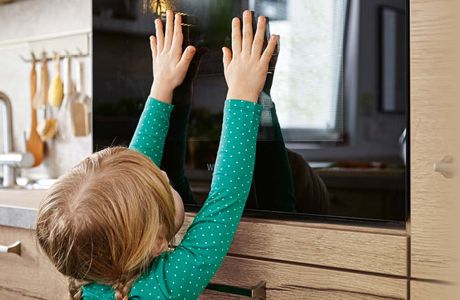 Kind legt Hände auf Backofentür